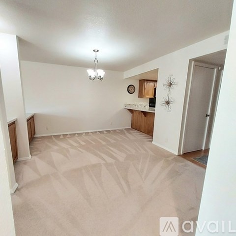 A spacious room with a patterned carpet and a chandelier hanging from the ceiling.