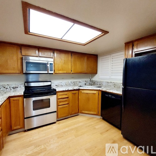 A kitchen with wooden cabinets and a black refrigerator.