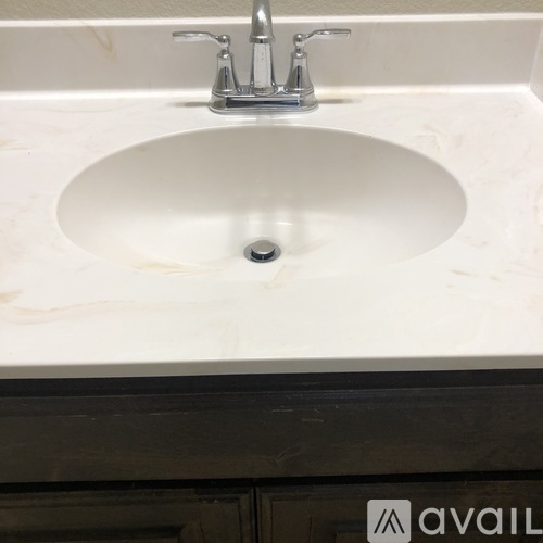 A white sink with a silver faucet in a marble countertop.