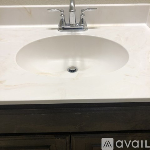 A white sink with a silver faucet in a marble countertop.