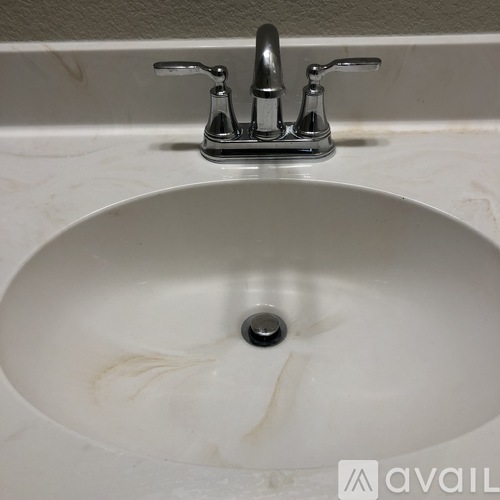 A white sink with a chrome faucet and a drain in the middle.