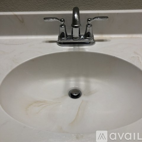 A white sink with a chrome faucet and a drain in the middle.