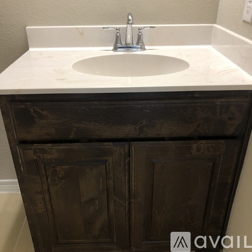 A white sink is on top of a wooden cabinet.
