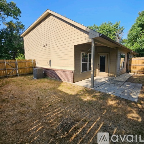 A small house with a porch and a fence in front.