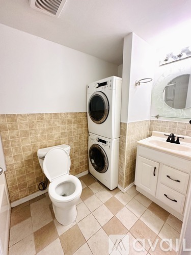 A small bathroom with a toilet, a washing machine, and a sink.