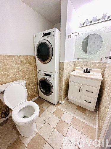 A white toilet is next to a washing machine in a bathroom.