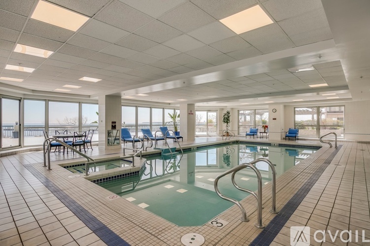 A large indoor swimming pool with lane markers and a few chairs around the perimeter.