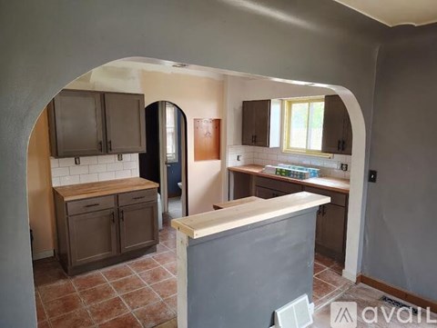 A kitchen with a refrigerator, cabinets, and a countertop is available for rent.