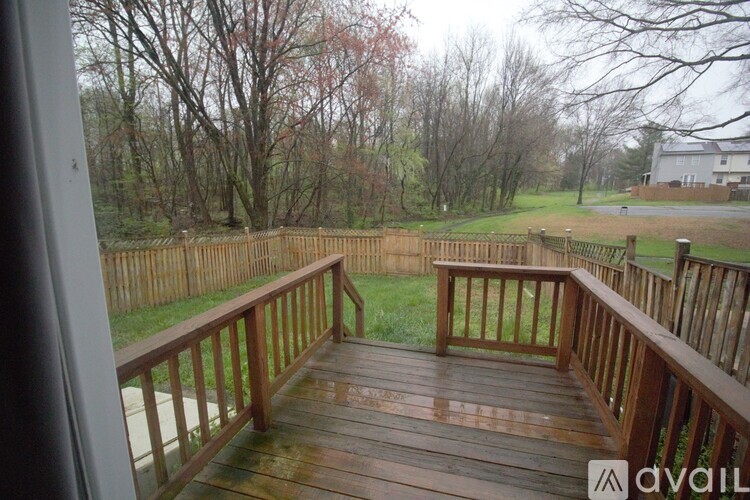A wooden deck with a view of a grassy area and trees.