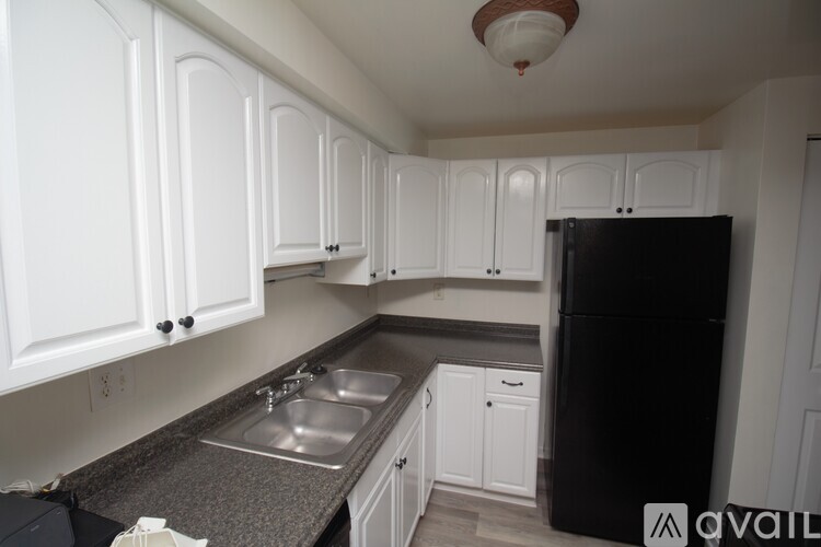 A kitchen with white cabinets and a black fridge.