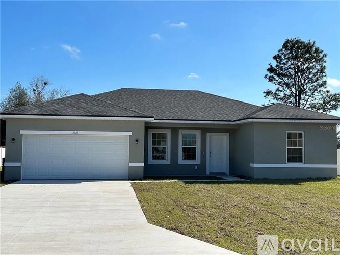 A house with a garage door and a tree in the background.