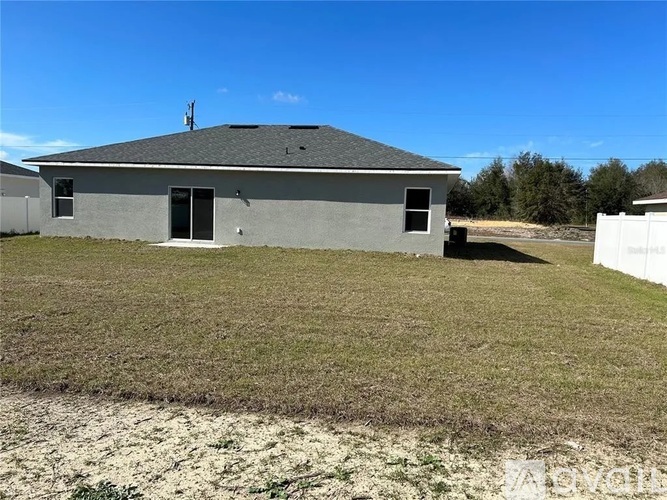 A grey house with a white fence in the front yard.