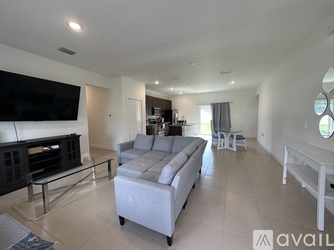 A living room with a grey sofa and a television on the wall.