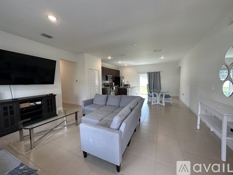 A living room with a grey sofa and a television on the wall.