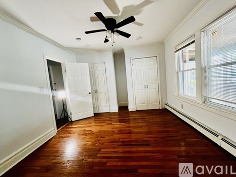 A room with a ceiling fan and wooden floors.