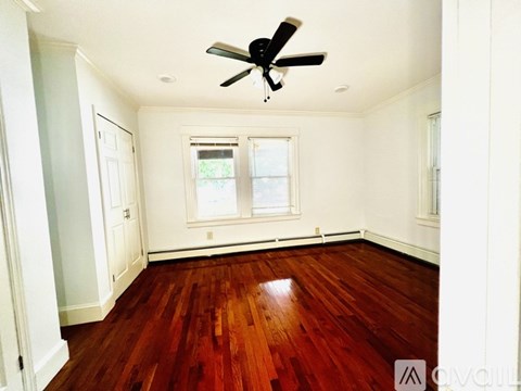 A room with a ceiling fan and wood flooring.