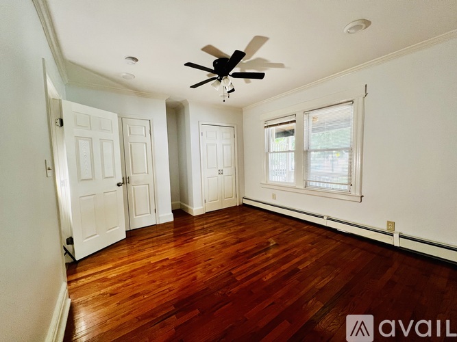 A room with a ceiling fan and wooden floors.