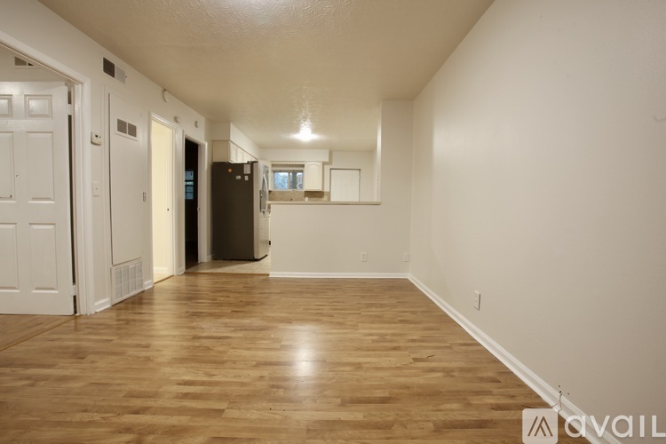 A spacious room with wooden flooring and white walls.