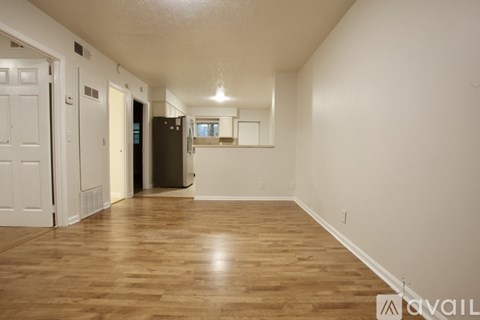 A spacious room with wooden flooring and white walls.