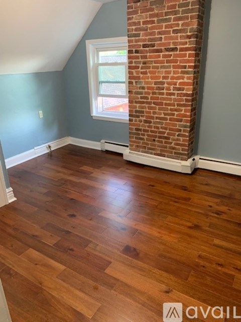 A room with wooden flooring and a brick pillar.