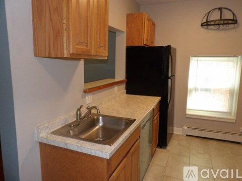 A kitchen with a black refrigerator and wooden cabinets.