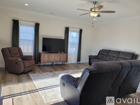 A living room with a brown recliner, a black leather chair, and a wooden entertainment center.