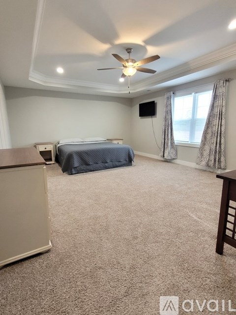 A bedroom with a bed, a dresser, and a ceiling fan.