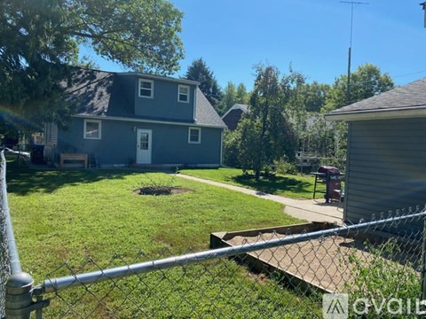A house with a grey roof and a fence in front of it.
