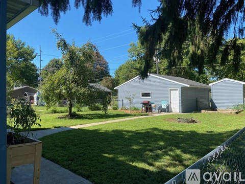 A backyard with a fence, a shed, and a lawn.
