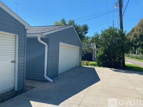 A grey garage with a white door is situated in a driveway.