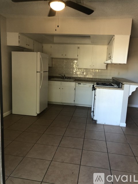 A kitchen with white appliances and a fan.
