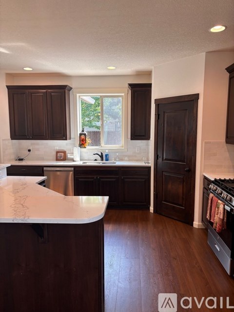 A kitchen with dark wood cabinets and a white countertop.