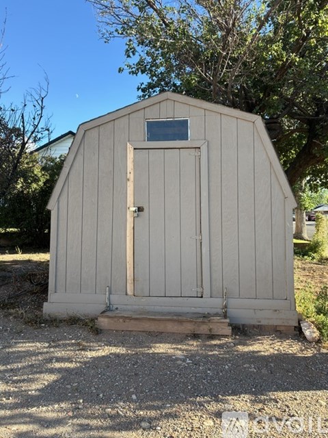 A small wooden shed with a door and a window.