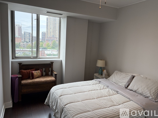 A bedroom with a large bed and a window overlooking a cityscape.