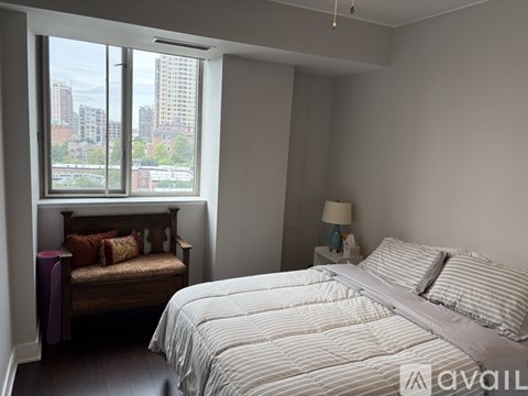 A bedroom with a large bed and a window overlooking a cityscape.