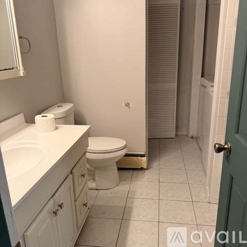 A bathroom with a toilet, sink, and mirror.