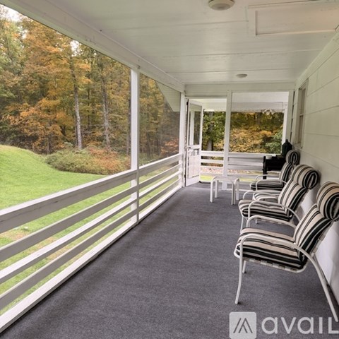 A row of chairs are lined up on a porch.
