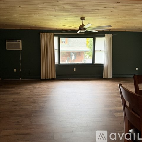 A room with a ceiling fan and a window with curtains.