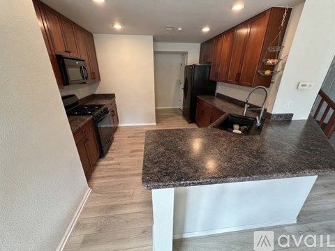 A kitchen with a granite countertop and wooden cabinets.