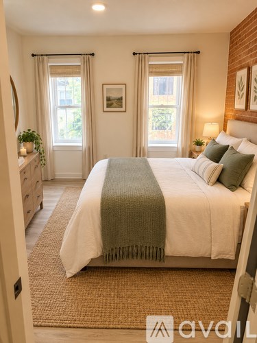 A bedroom with a large bed and a window with curtains.