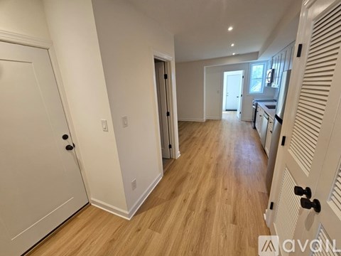 A spacious room with wooden flooring and white walls.