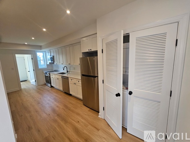 A kitchen with white cabinets and a wooden floor.