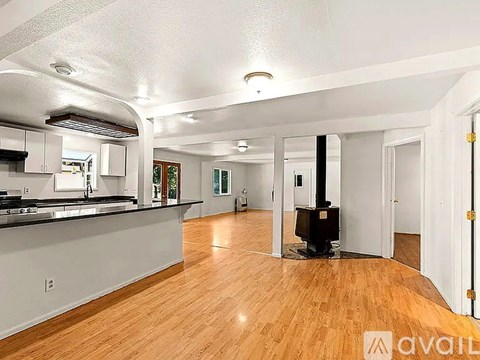 A spacious living room with wood flooring and a black stove.