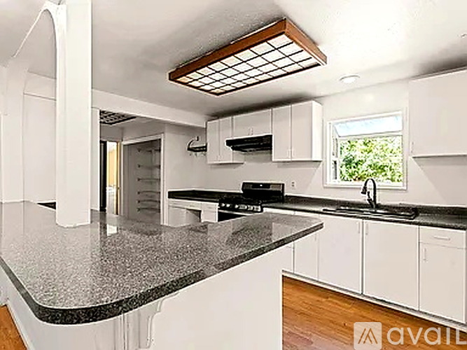 A kitchen with white cabinets and a granite countertop.