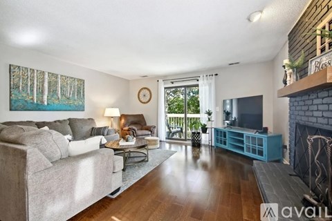 A living room with a grey couch and a painting of a forest on the wall.