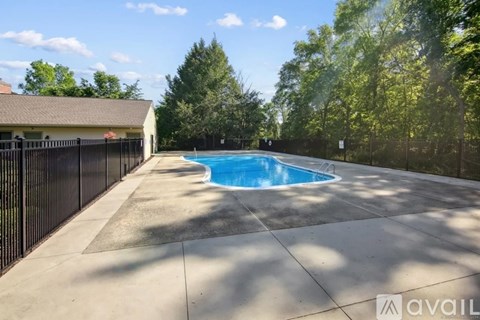 A pool surrounded by a black fence with a house in the background.