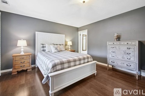 A bedroom with a bed, nightstand, and dresser.
