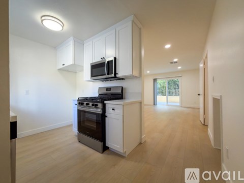 A kitchen with white cabinets and a black microwave.