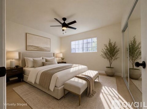 A bedroom with a large bed and a ceiling fan.