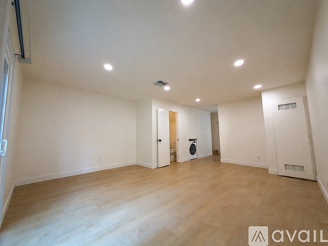 A spacious room with wooden flooring and white walls.
